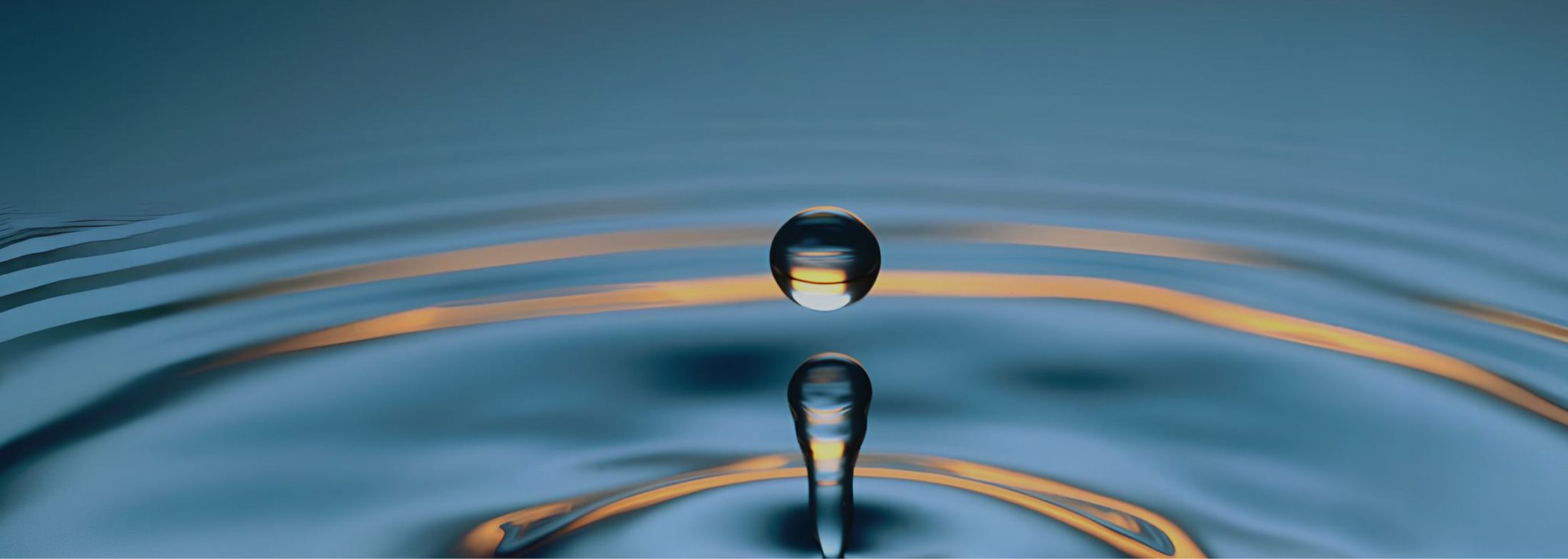Wassertropfen, der in ruhiges Wasser fällt und konzentrische Wellen erzeugt.