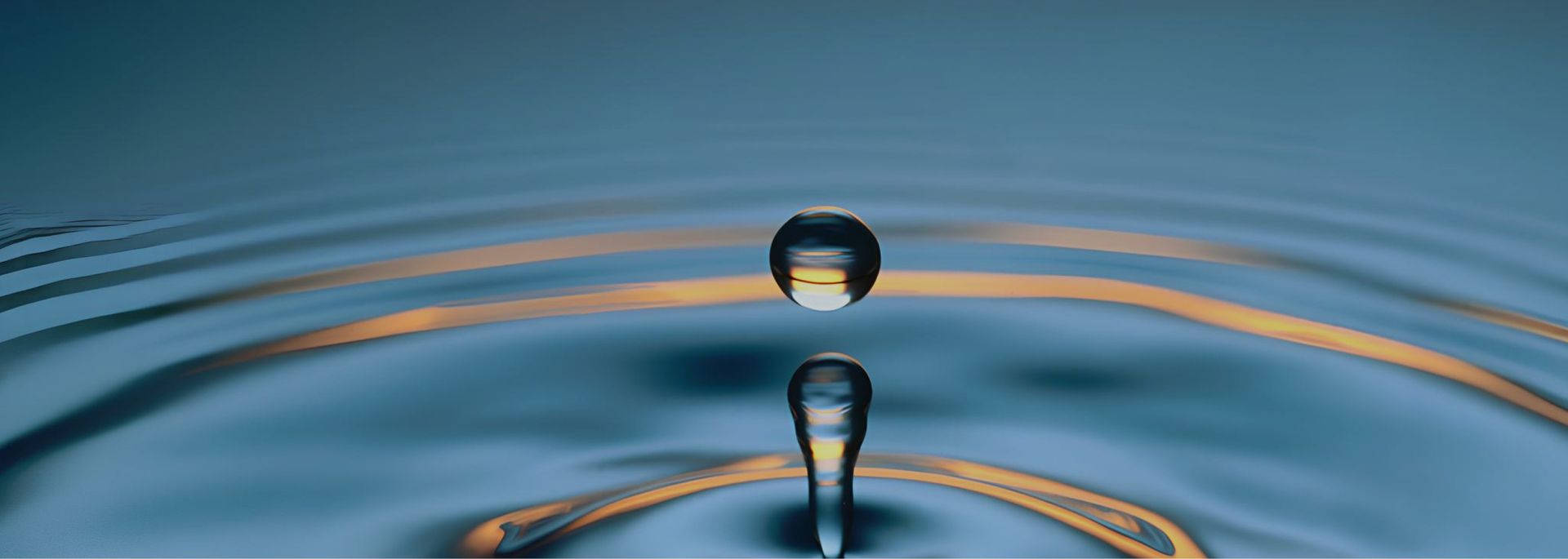 Wassertropfen, der in ruhiges Wasser fällt und konzentrische Wellen erzeugt.